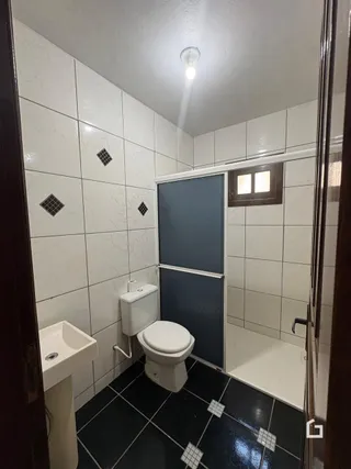 Foto de um banheiro com revestimento de azulejos brancos e piso escuro.