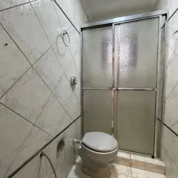 Foto de um banheiro com paredes revestidas em azulejos brancos.