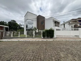 Fachada de uma residência em Lajeado, Brasil, com cerca e portão branco.