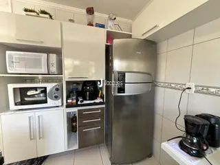 Interior de uma cozinha moderna com armários brancos e eletrodomésticos de aço inoxidável.