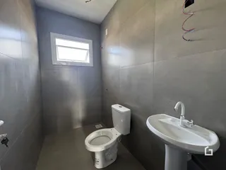 Foto de um banheiro com revestimento de cerâmica e louças brancas.