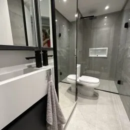 Banheiro com box de vidro e revestimento claro.