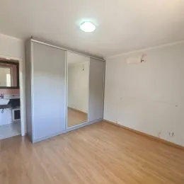 Quarto com piso de madeira e armários embutidos brancos.