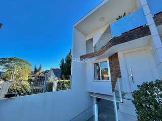 Fachada de uma casa moderna em Lajeado, Brasil com telhado branco e detalhes em pedra.