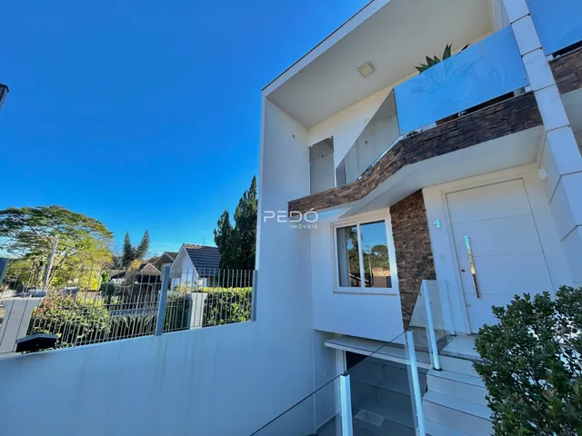 Fachada de uma casa moderna em Lajeado, Brasil com telhado branco e detalhes em pedra.