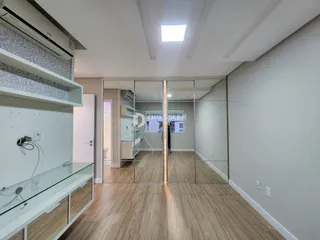 Vista interna de uma sala com piso de madeira clara e divisórias de vidro.