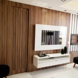 Parede revestida em painéis de madeira escura em um ambiente interno.