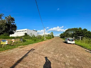 Vista de uma estrada pavimentada em uma área rural com um grande edifício ao fundo.