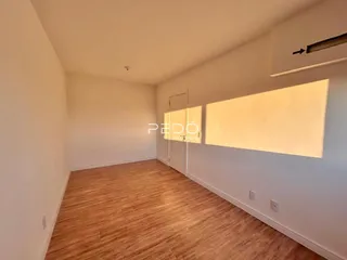 Ambiente interno de uma sala com piso de madeira clara e paredes brancas.