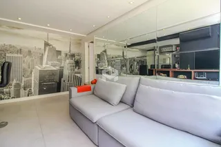 Sala de estar moderna com sofá cinza e decoração de parede de paisagem urbana.
