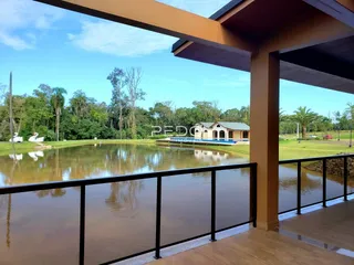 Vista de uma propriedade com água e vegetação ao fundo.