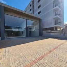 Fachada de um edifício residencial com grandes janelas e área pavimentada.