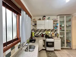 Vista da cozinha com armários brancos e grandes janelas.