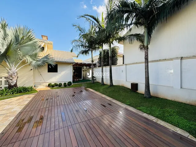 Vista externa de uma propriedade com deck de madeira e gramado verde.