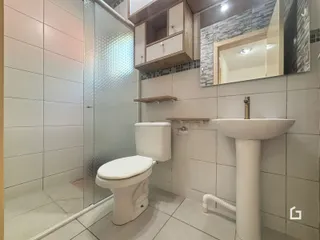Foto interna de um banheiro com revestimento cerâmico e box de vidro.