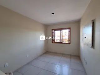 Vista interna de um cômodo com piso de cerâmica e janela de madeira.