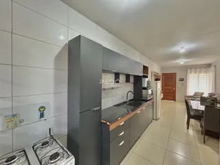 Esta é uma cozinha com armários cinzas e bancada escura.