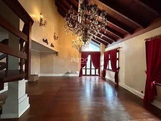 Sala ampla com piso de madeira e teto alto em imóvel no Brasil.