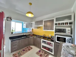 Cozinha moderna com armários de madeira e bancada escura em um ambiente claro.
