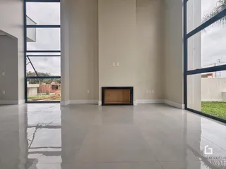 Ambiente interno de uma sala ampla com grandes janelas e piso claro.