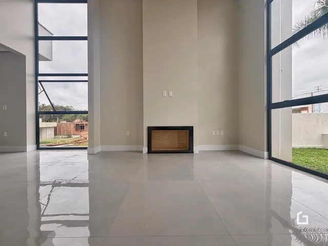 Ambiente interno de uma sala ampla com grandes janelas e piso claro.