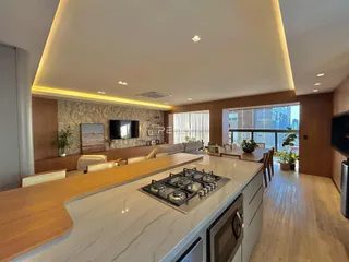 Vista da cozinha moderna com ilha e área de estar em um apartamento em Lajeado.