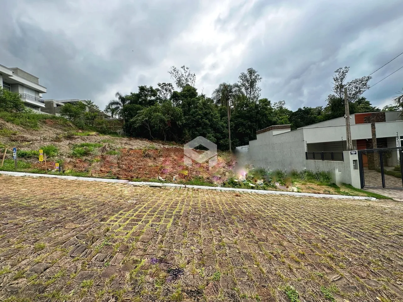 Vista externa de uma propriedade com terreno inclinado e vegetação densa.