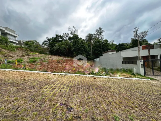 Vista externa de uma propriedade com terreno inclinado e vegetação densa.