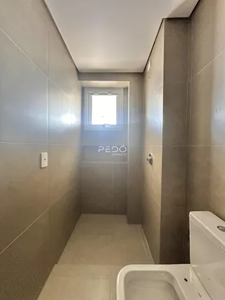Corredor interno com revestimento de cerâmica e porta de janela em um imóvel.