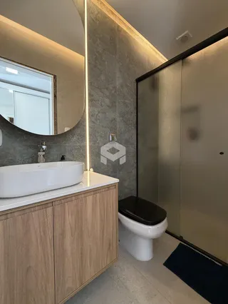 Banheiro moderno com bancada de madeira e box de vidro.