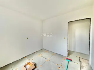 Interior de um cômodo em reforma com piso de concreto exposto.