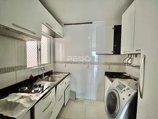 Foto de uma cozinha com armários brancos e bancada escura.