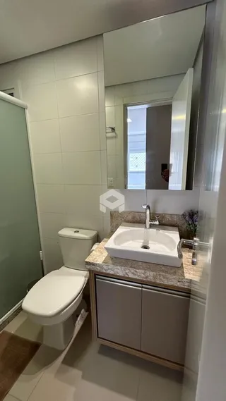 Foto de um banheiro com louças sanitárias e bancada de mármore.