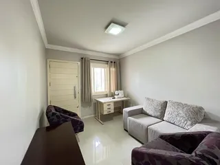 Sala de estar clara com sofá e cortinas brancas.