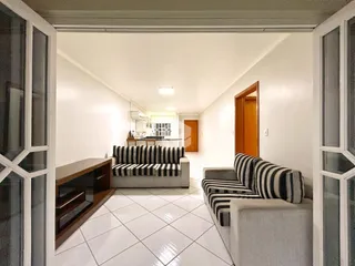 Sala de estar com piso de cerâmica e dois sofás em um apartamento.