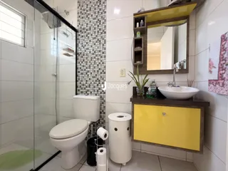 Banheiro com piso cerâmico e box de vidro.