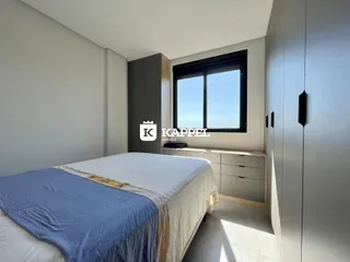 Quarto com cama e armário em um apartamento com vista para o mar.