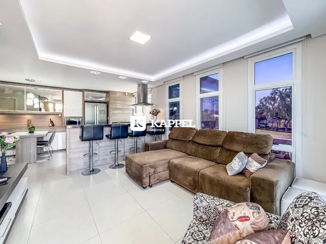 Sala de estar moderna com sofá grande e cozinha integrada.