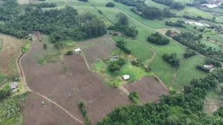 Vista aérea de uma propriedade rural com campos e vegetação densa.