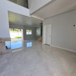 Sala de estar ampla com piso claro e paredes brancas.