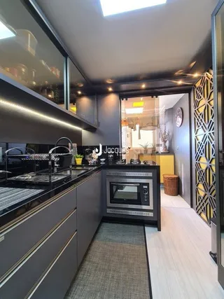 Uma cozinha moderna com armários escuros e eletrodomésticos de aço inoxidável.