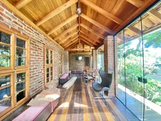 Interior com teto de madeira e paredes de tijolo aparente em uma residência.