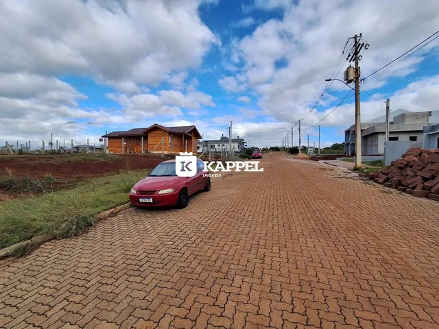 Vista externa de uma propriedade rural com estruturas de madeira e um veículo na estrada.