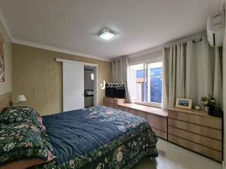 Quarto com cama e painel de madeira na sala.