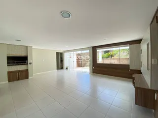 Ambiente interno de uma sala de estar ampla com piso de cerâmica clara.