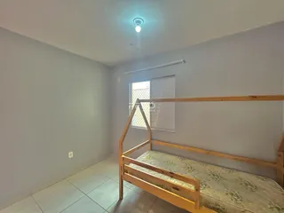 Quarto com cama de madeira e piso cerâmico claro.