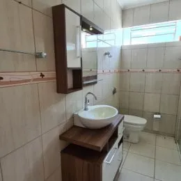 Foto interna de um banheiro com revestimento de azulejos claros e uma bancada.