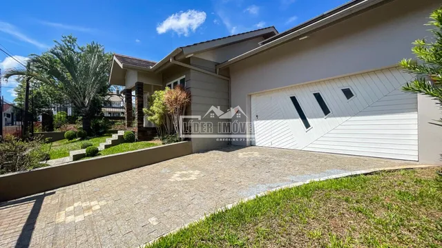 Fachada de uma residência com garagem e paisagismo em Lajeado.