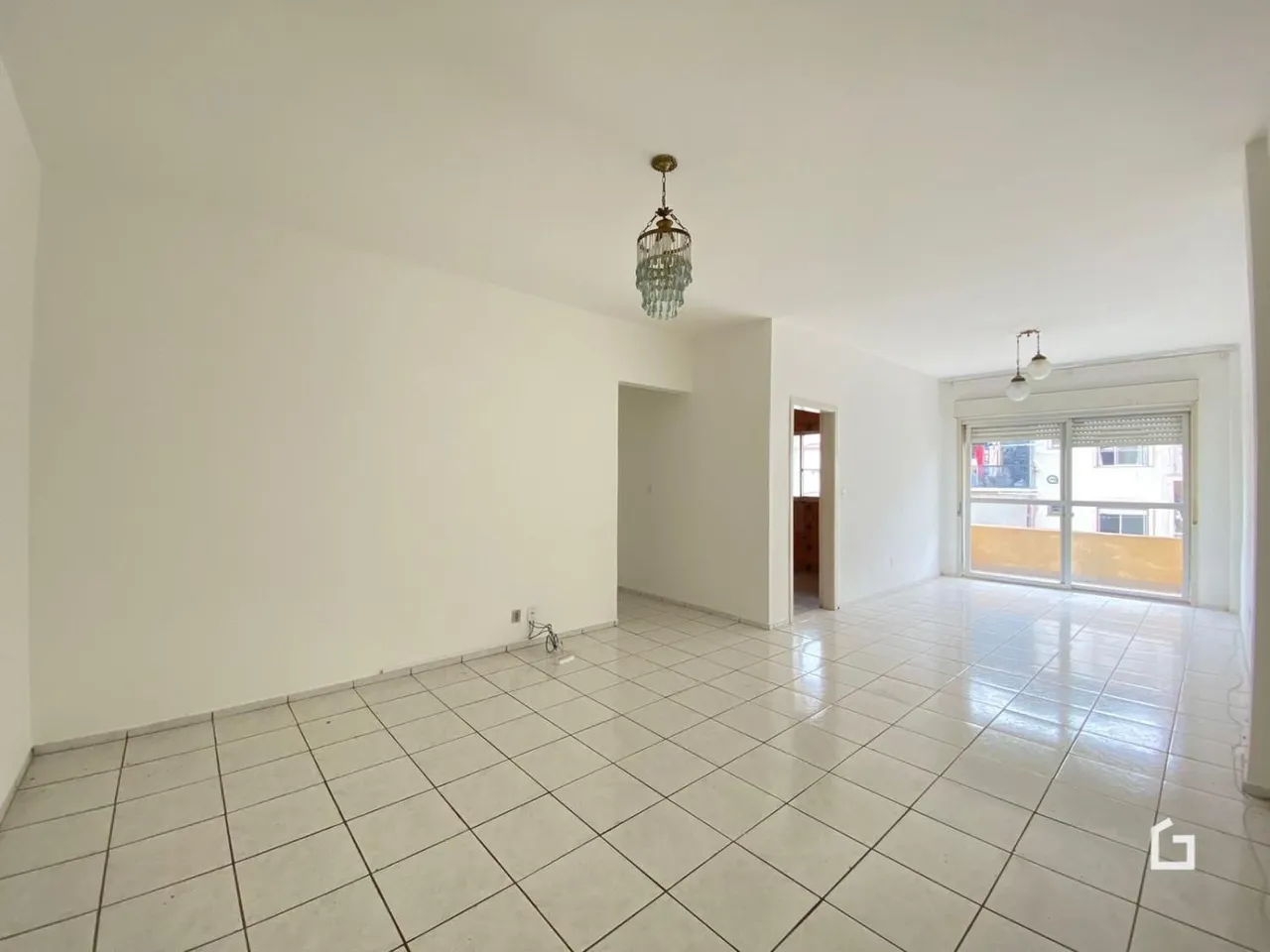 Ambiente interno de uma sala com piso de cerâmica clara e paredes brancas.