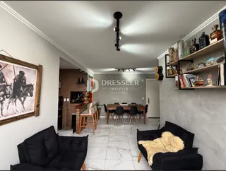 Sala de estar com sofá preto e prateleiras de madeira na parede.